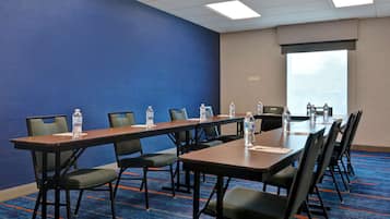 Una sala de conferencias con pared azul, un ventanal grande y piso alfombrado.