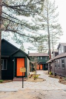 Uma fileira de casas com um caminho de pedra que leva a uma porta verde com a placa 'Noon Lodge'.