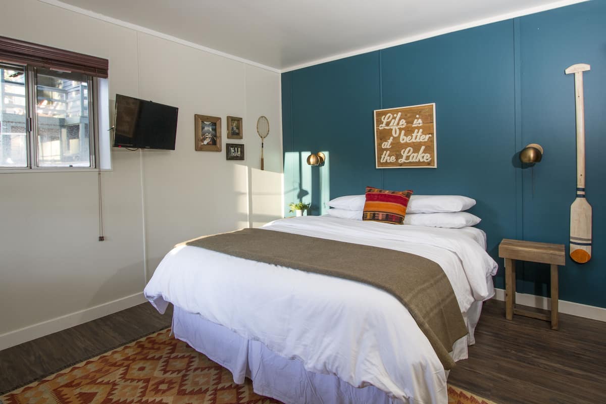 Une chambre à coucher avec un lit, une télévision, une fenêtre et un mur sur lequel est accroché un panneau.