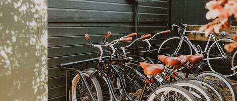Bicycles parked against a wooden wall in a covered area with a tiled floor.