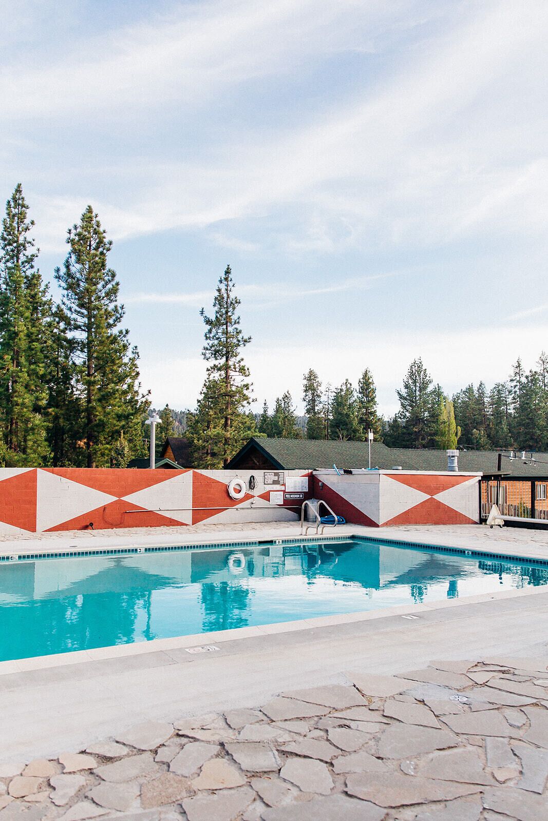 Une piscine ornée d’un motif à chevrons rouge et blanc, et entourée de carreaux de pierre.