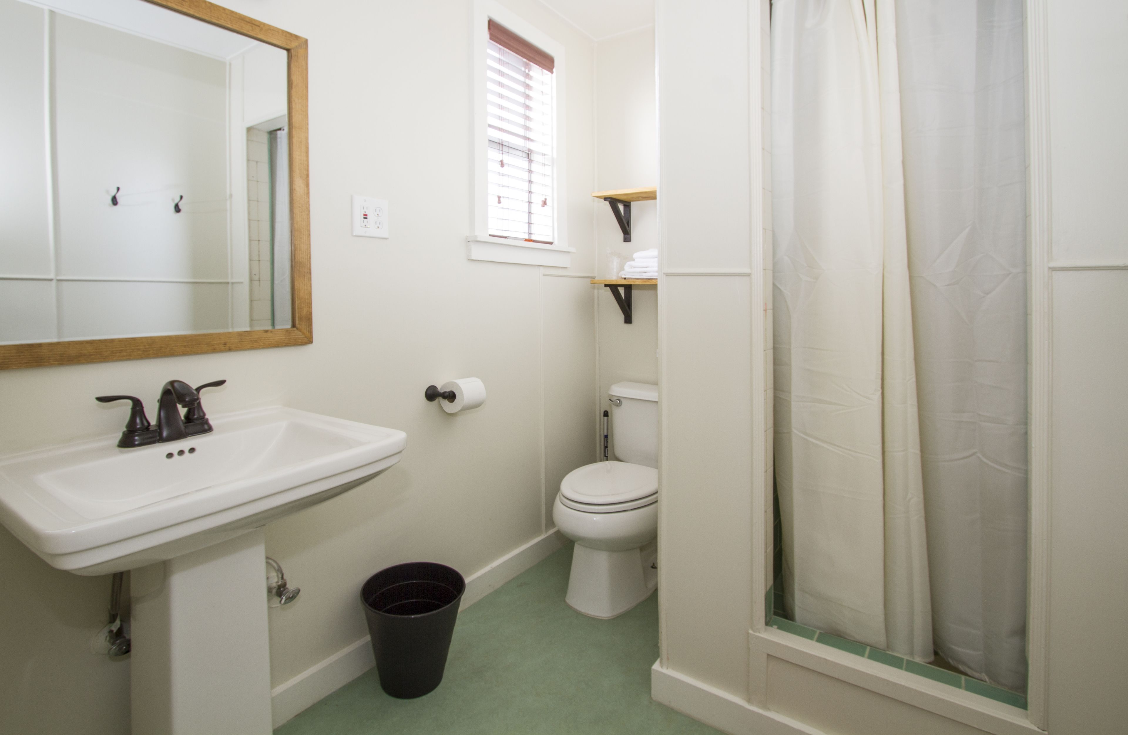 Une salle de bain avec un lavabo blanc, des toilettes et un rideau de douche.