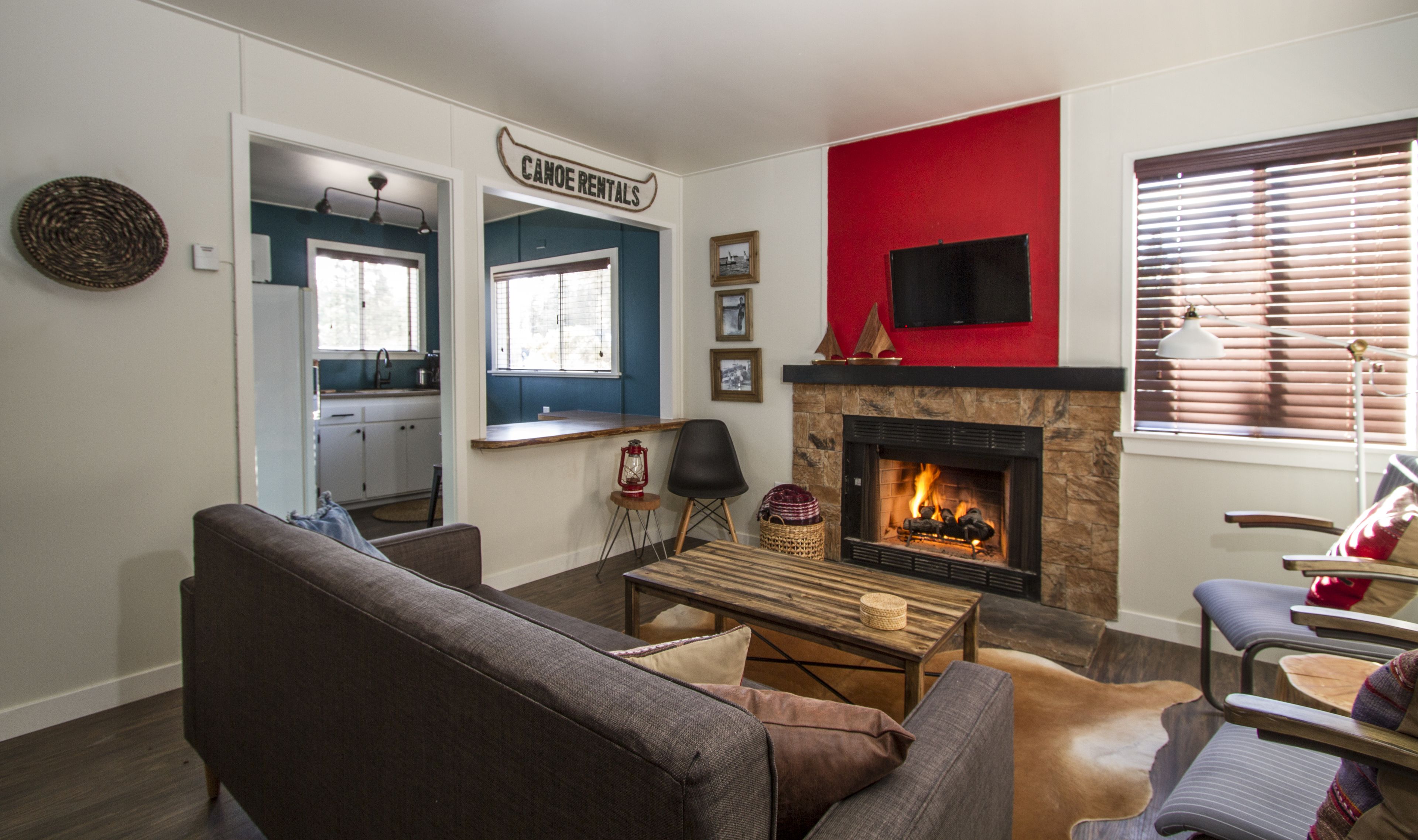 Una sala de estar con chimenea, un sofá, una mesa de centro y un televisor montado en la pared.