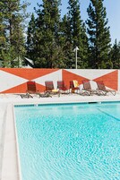 Ein Schwimmbecken mit Liegestühlen und einer Wandgestaltung im geometrischen Stil.