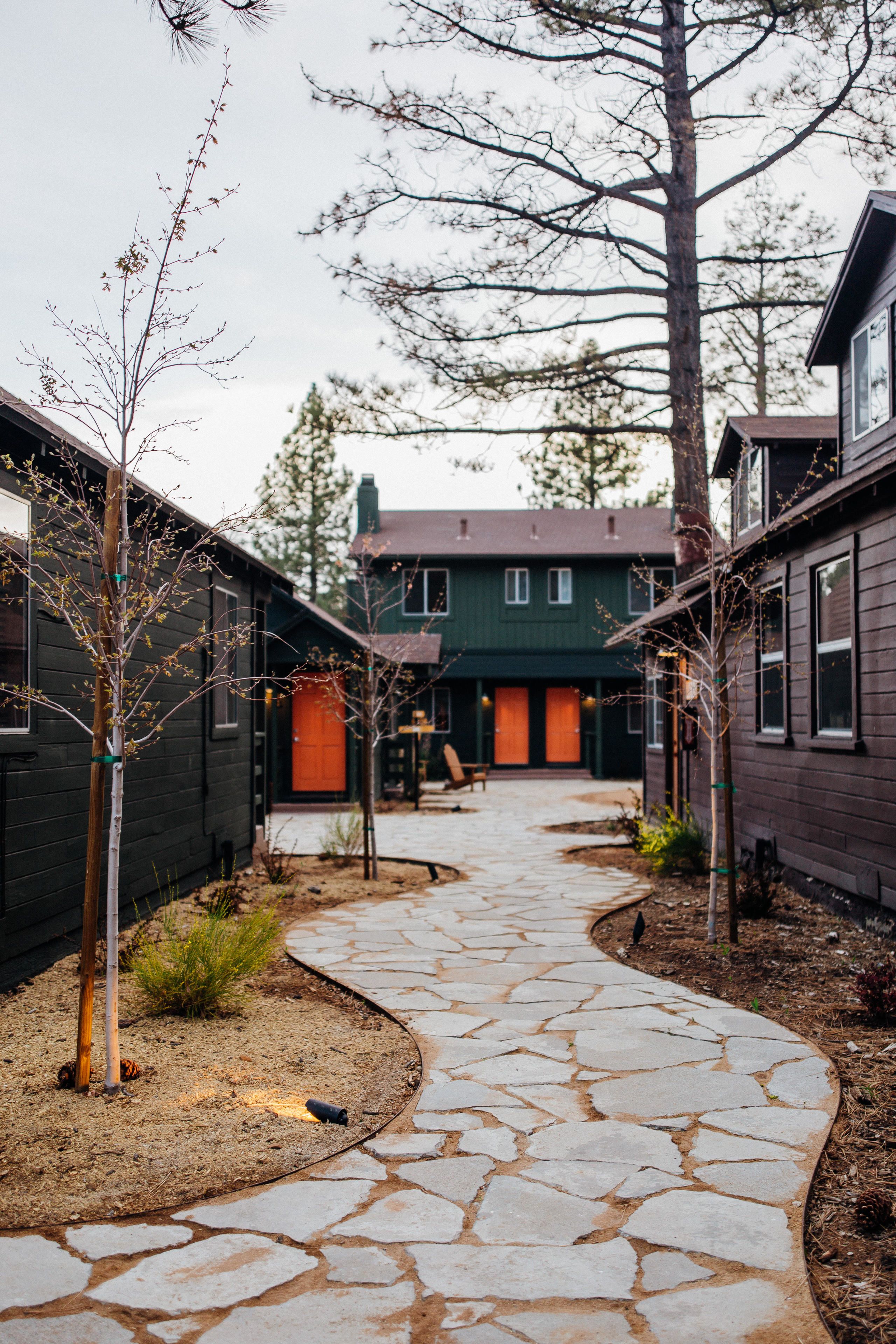 A stone pathway leading to a building with a green door and a brown door.