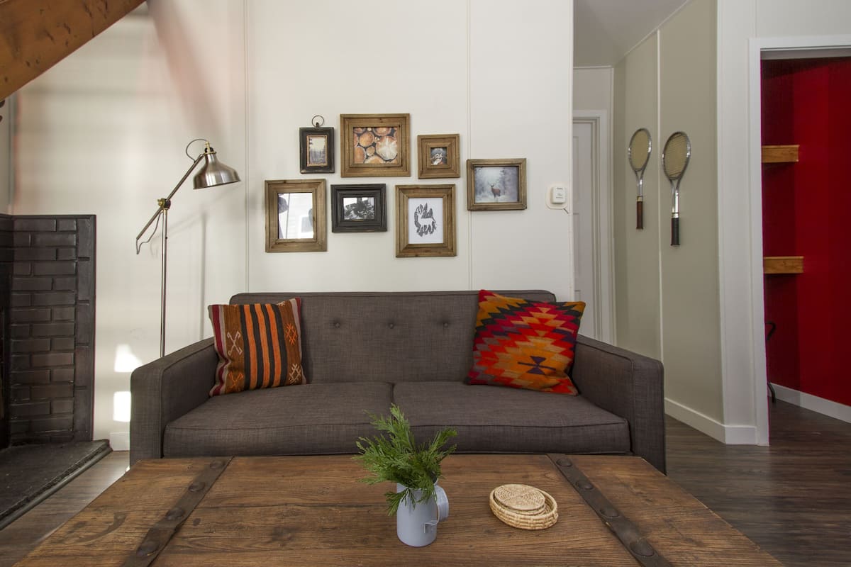 Un salon avec un canapé gris, une table basse en bois et une cheminée.