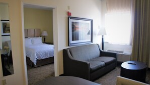 A hotel room with a bed, a sofa, a small table, and a chair.