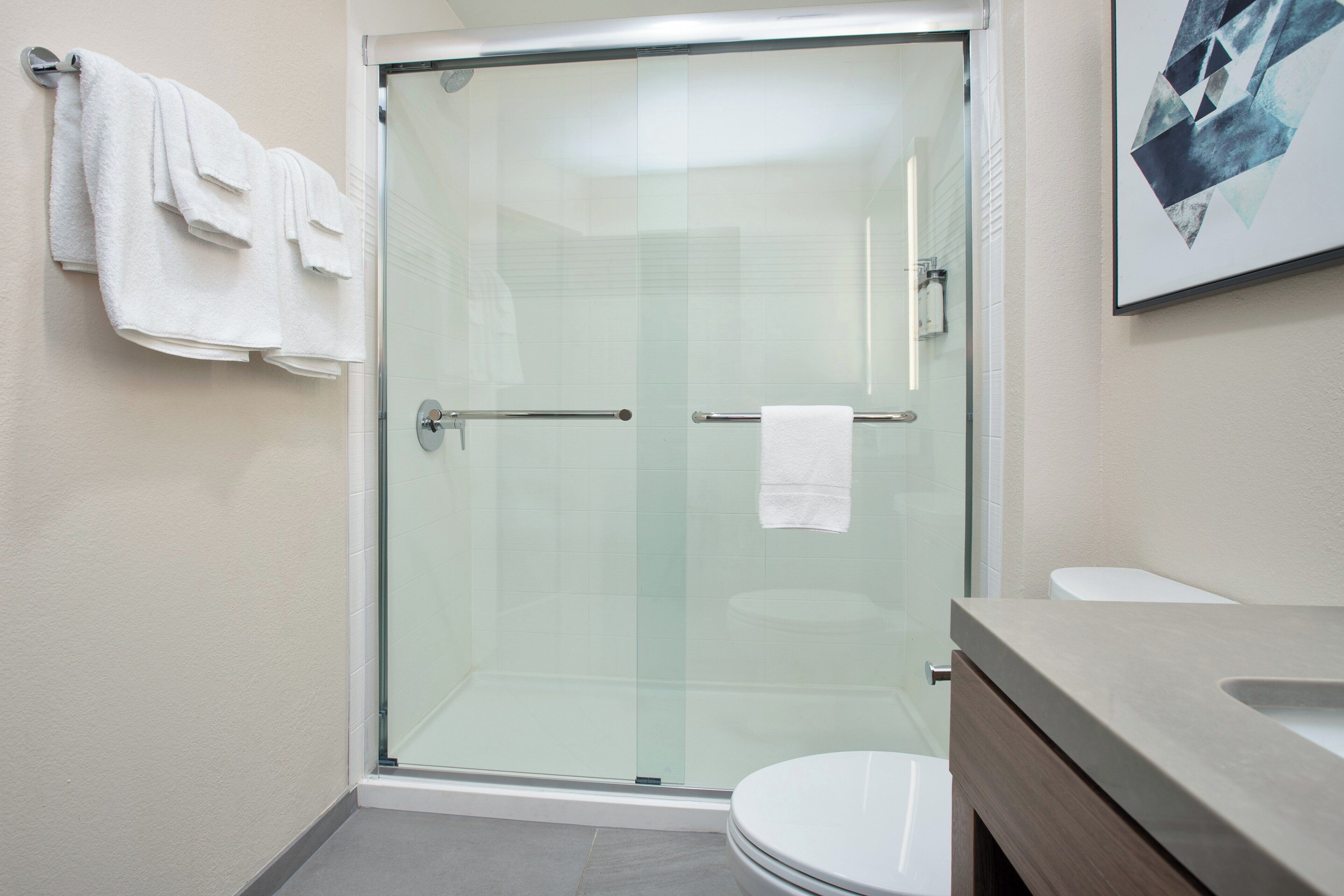 Un baño moderno con cabina de ducha de vidrio, inodoro y tocador con encimera.