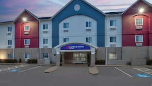 A multi-story hotel with a blue and red facade, a central entrance, and a parking lot with handicapped parking spaces. - Candlewood Suites Conway by IHG (Conway)