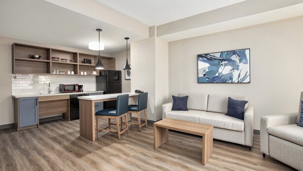 A modern living room with a sofa, coffee table, and dining area. - Candlewood Suites Conway by IHG (Conway)