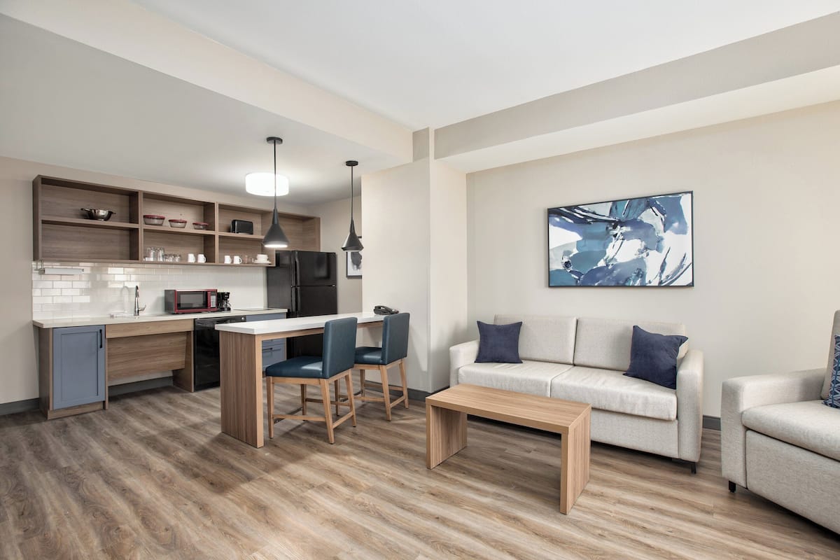 A modern living room with a sofa, coffee table, and dining area.