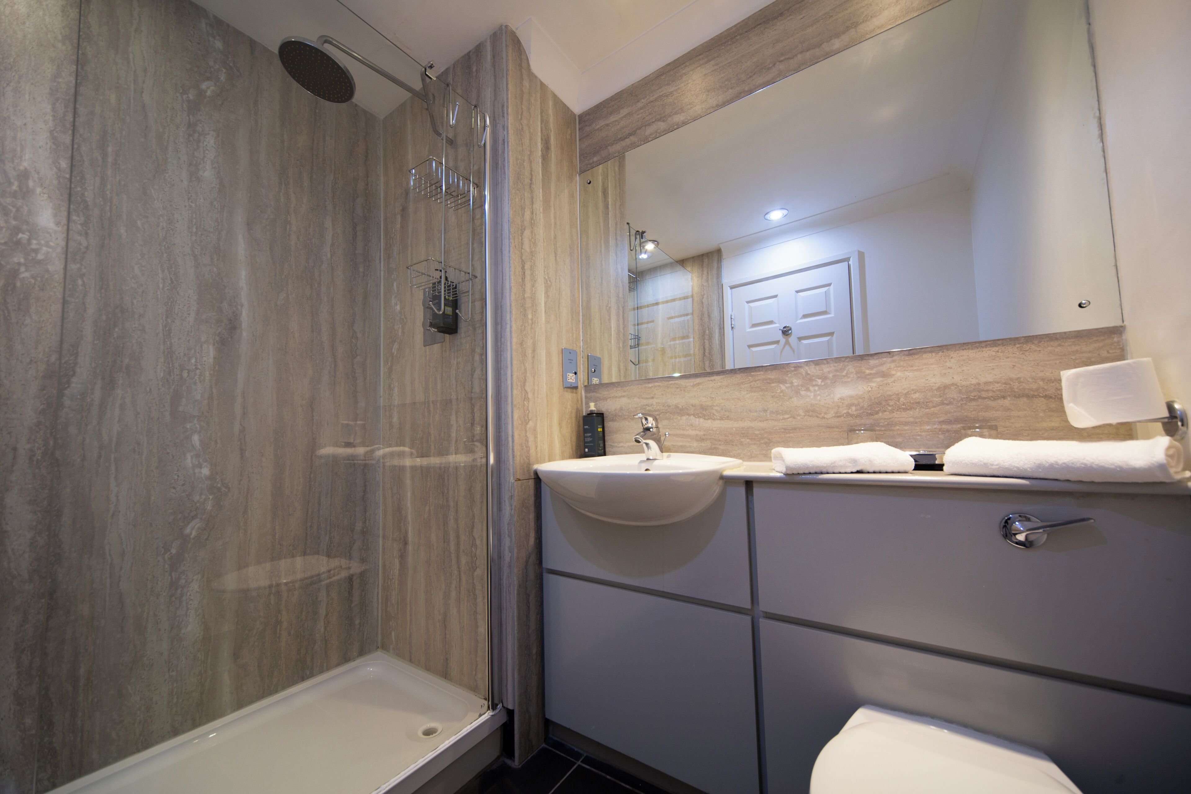 A modern bathroom with a shower, sink, and toilet.