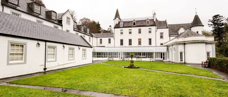 A large, white building with multiple windows and a central courtyard with a fountain.