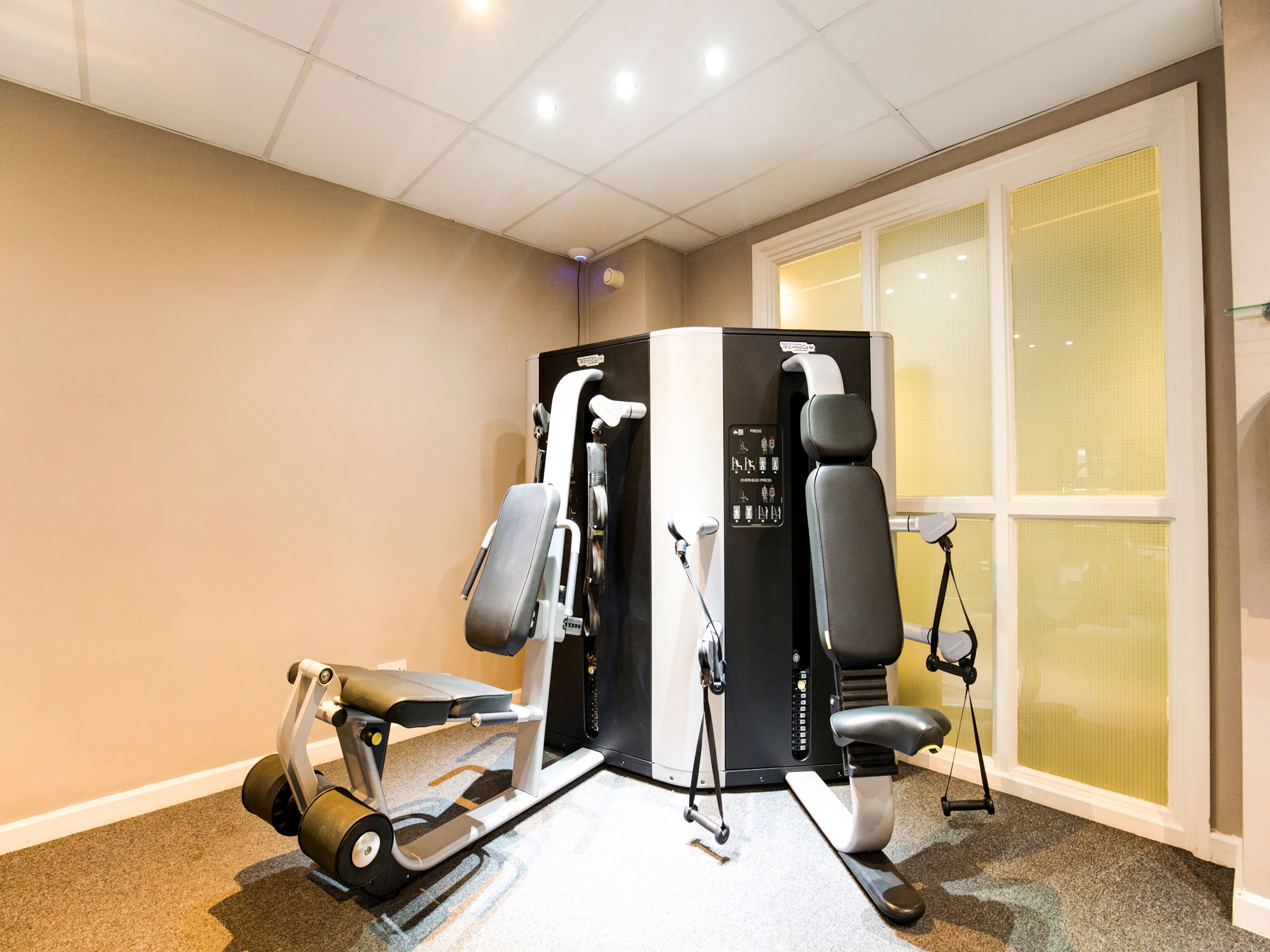 A gym with exercise equipment including a treadmill, elliptical, and weight machines.