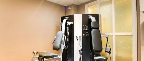 A gym with exercise equipment including a treadmill, elliptical, and weight machines.