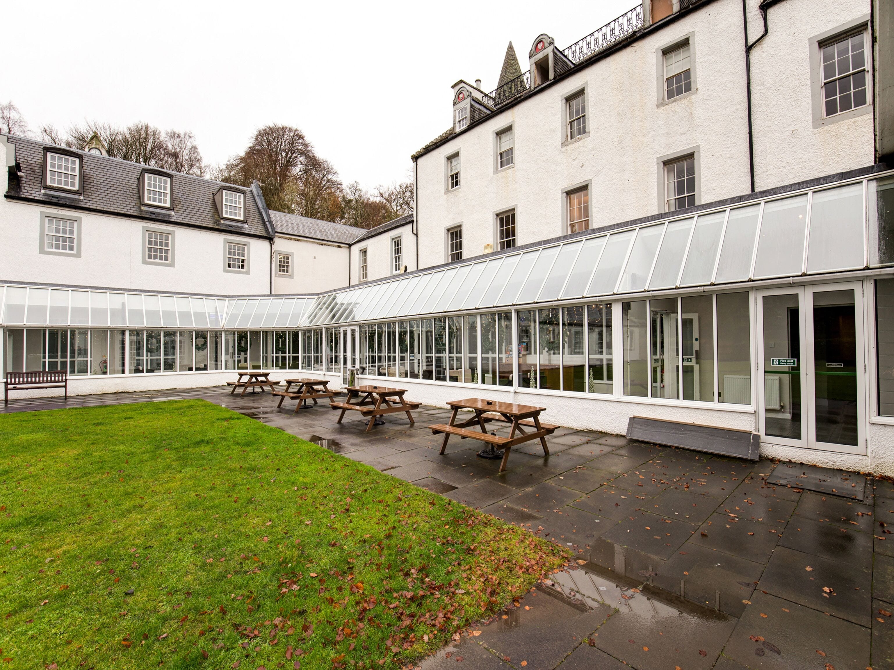 A courtyard with picnic tables and a greenhouse structure.