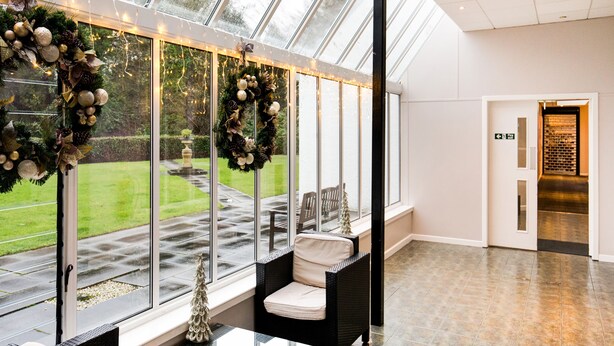 A spacious room with large windows, a seating area with a sofa and chairs, and a view of a garden.