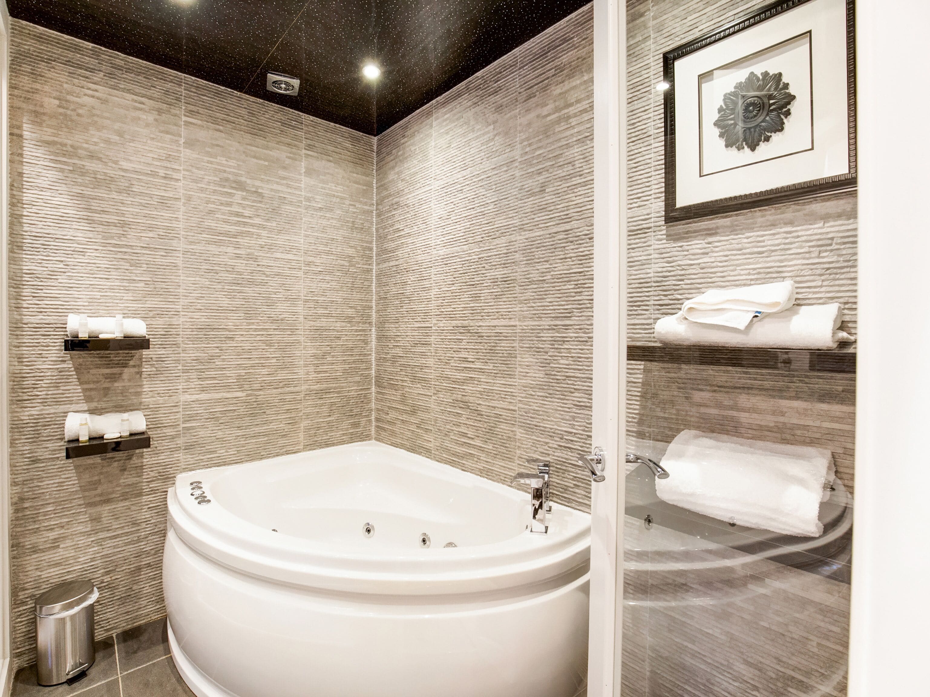 Un baño moderno con una bañera independiente grande, cabina de ducha y una obra de arte enmarcada en la pared.
