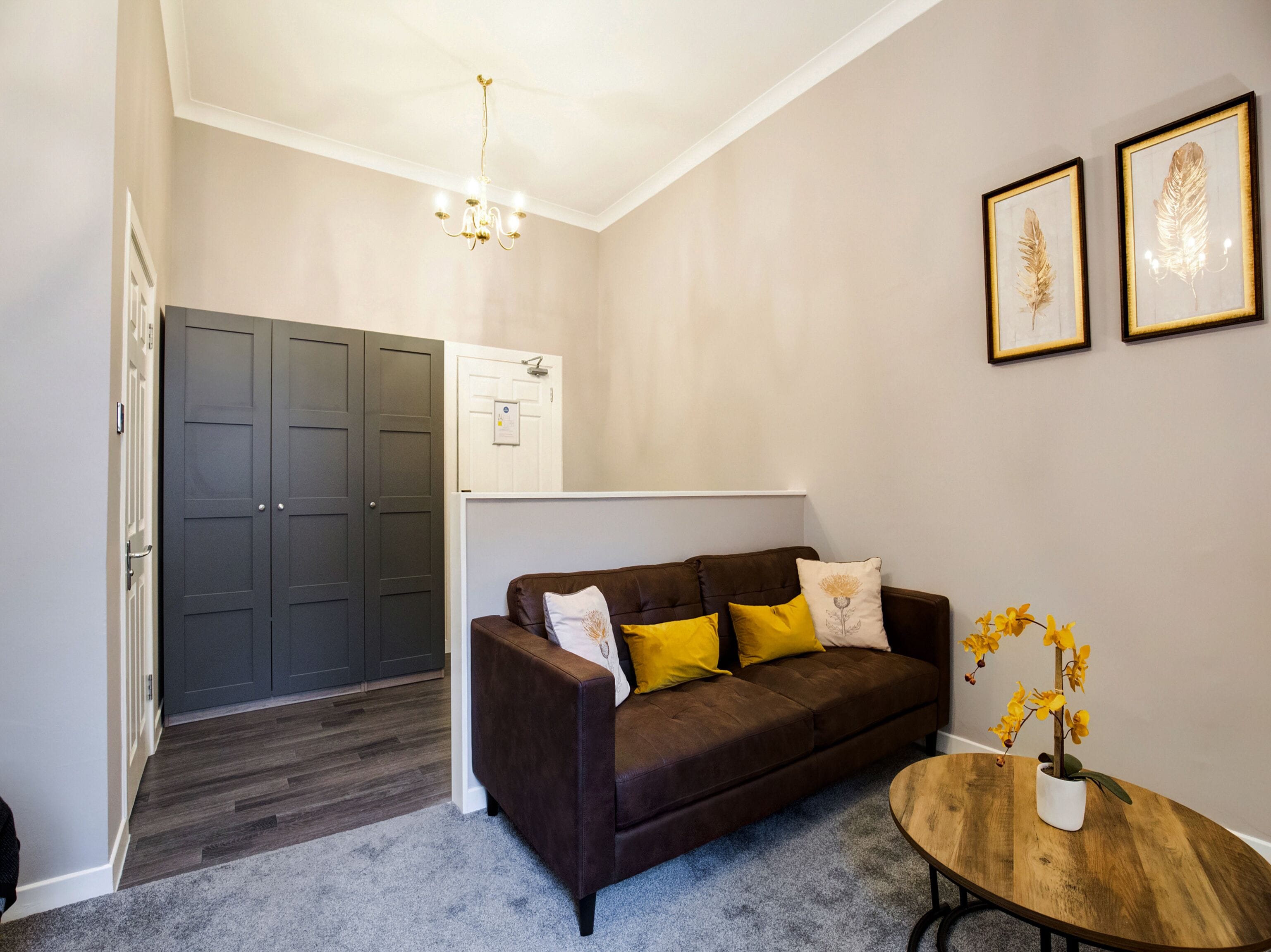 A living room with a brown sofa, a wooden coffee table, and a door leading to a hallway.