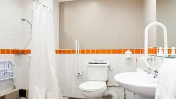 Un baño con inodoro, lavamanos y ducha. El piso tiene un diseño de cuadros.