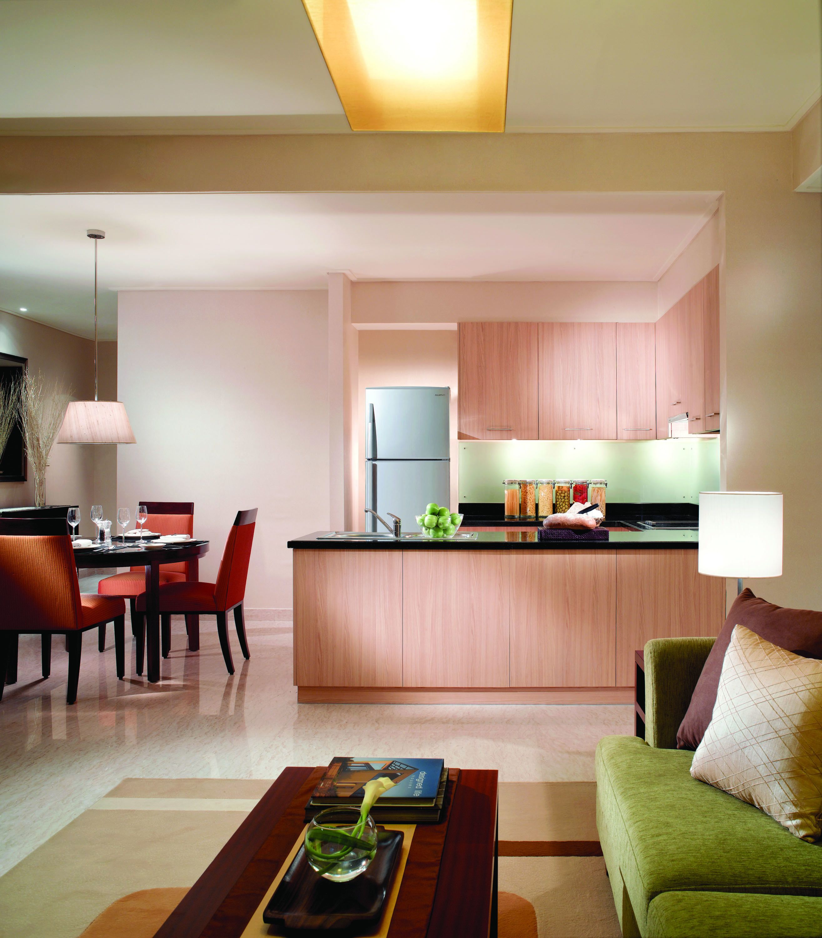 A modern kitchen with wooden cabinets, a built-in refrigerator, and a dining area with a table and chairs.