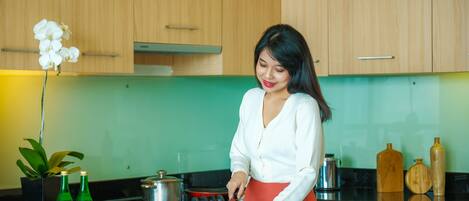 A kitchen with wooden cabinets, a green backsplash, and a person preparing fruit.
