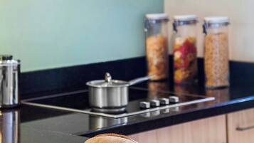 Un plan de travail de cuisine avec deux pains, une planche à découper, un couteau et trois bocaux en verre contenant divers aliments.