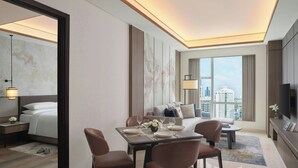 Ein modernes Hotelzimmer mit Essbereich, einem großen Bett, einem Fernseher und Blick auf die Stadt.