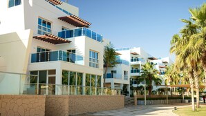 A modern hotel with multiple balconies, large windows, and a stone facade.