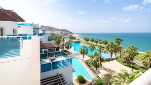 A resort with a pool, palm trees, and a view of the ocean.