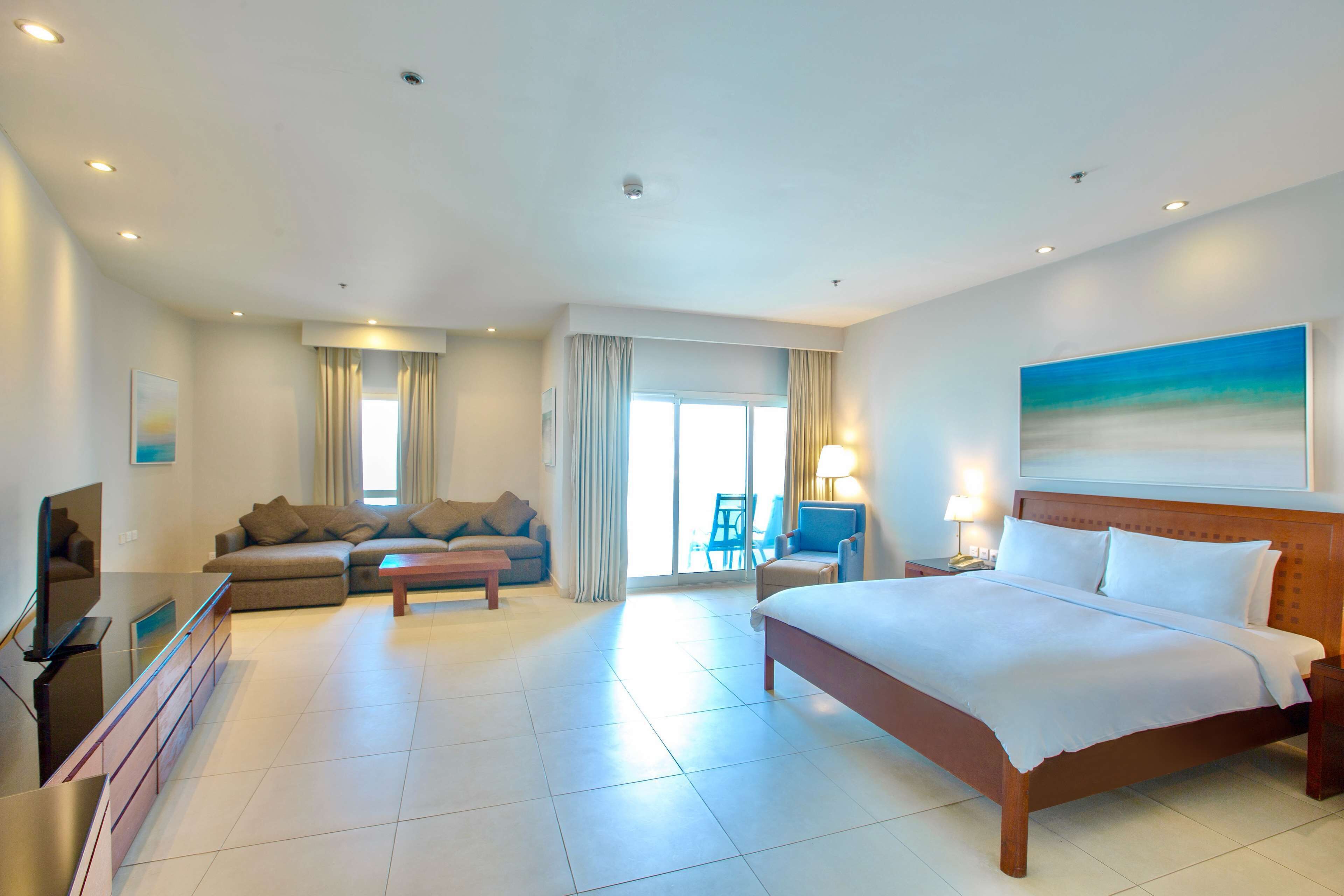 Une chambre d’hôtel moderne équipée d’un grand lit, d’un canapé, d’une télévision et d’un bureau.