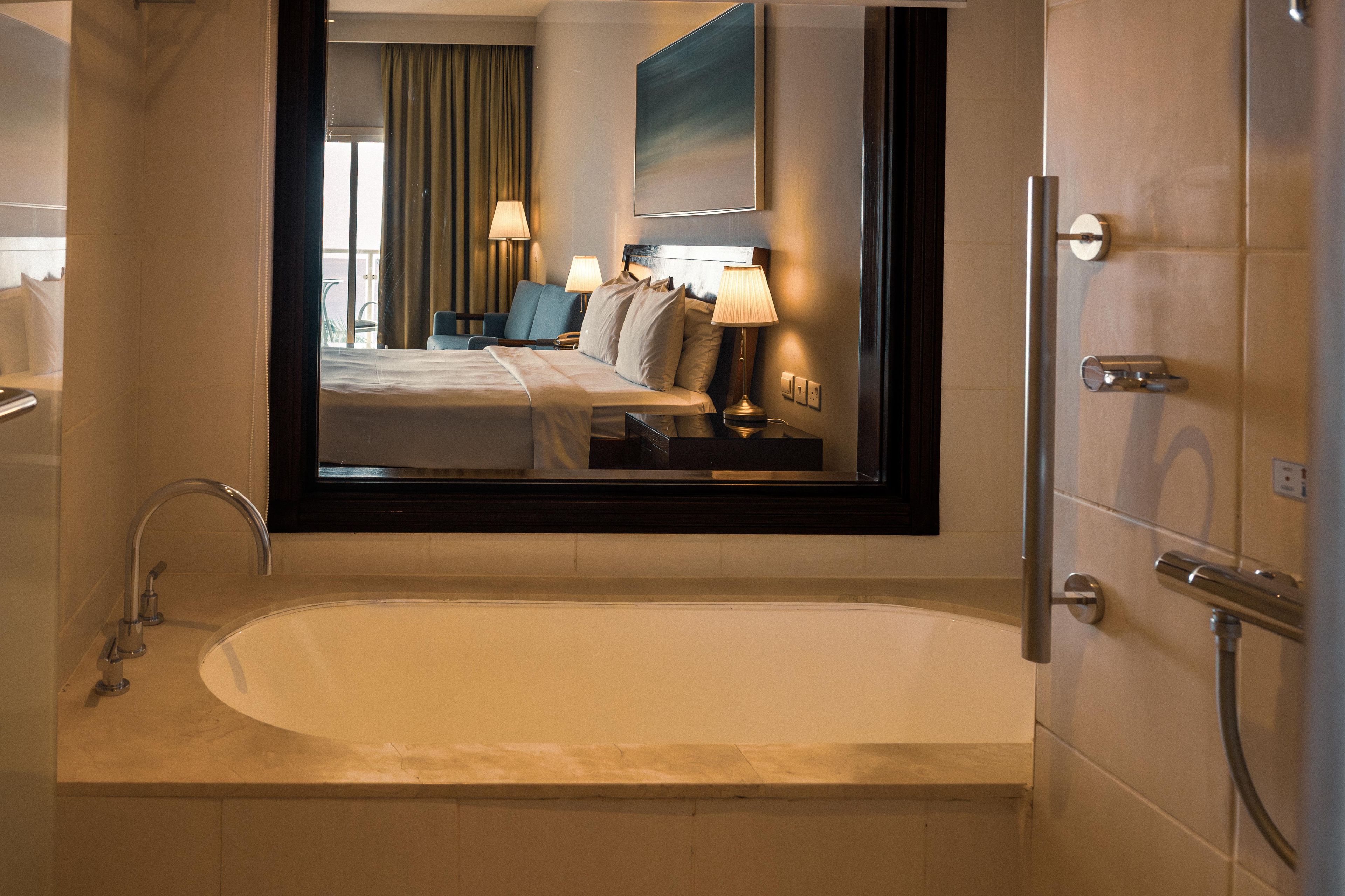 A hotel bathroom with a large bathtub, a mirror, and a shower area.