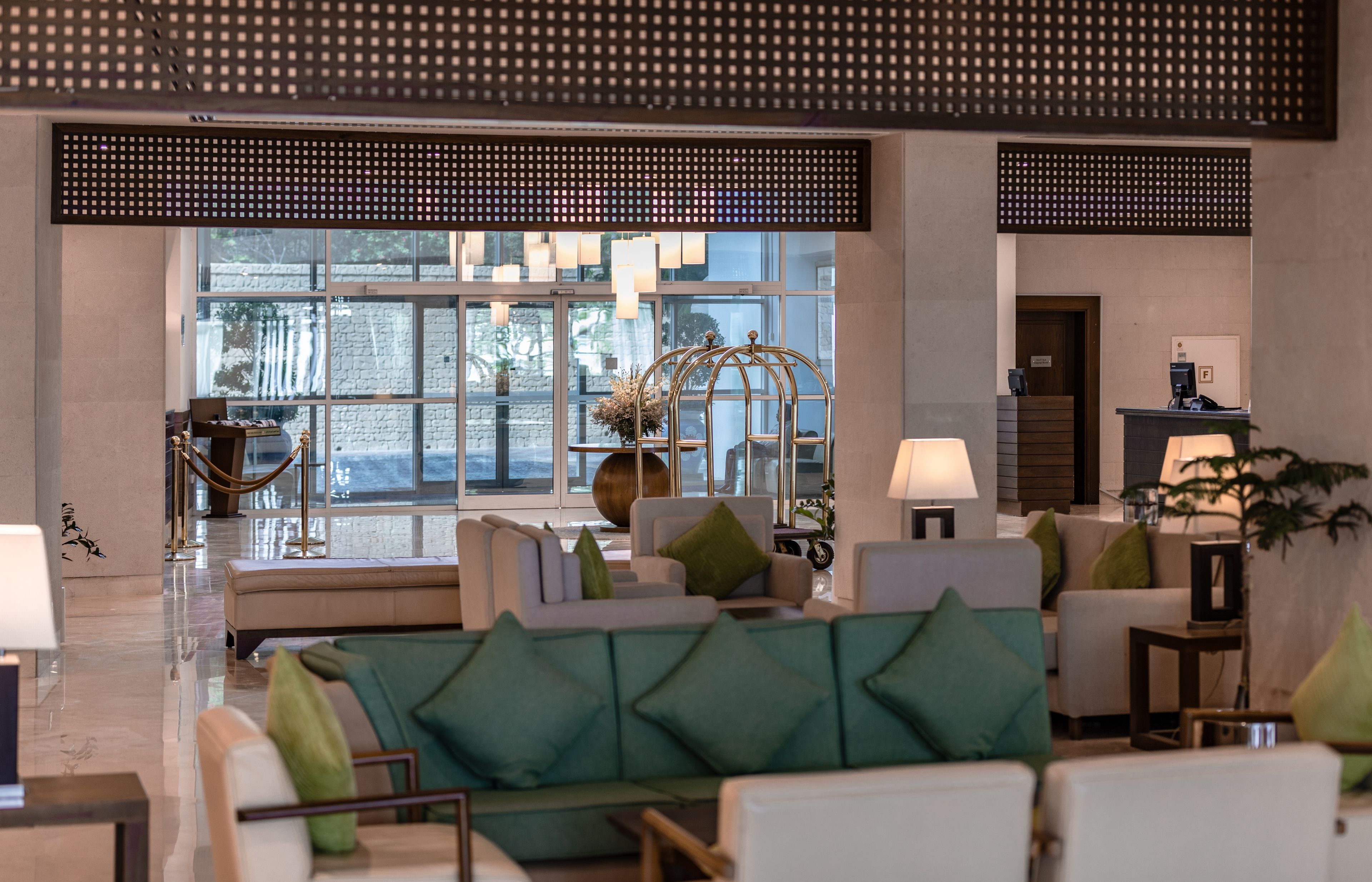A spacious lobby with a modern design, featuring a seating area with sofas and armchairs, a reception desk, and large windows providing natural light.