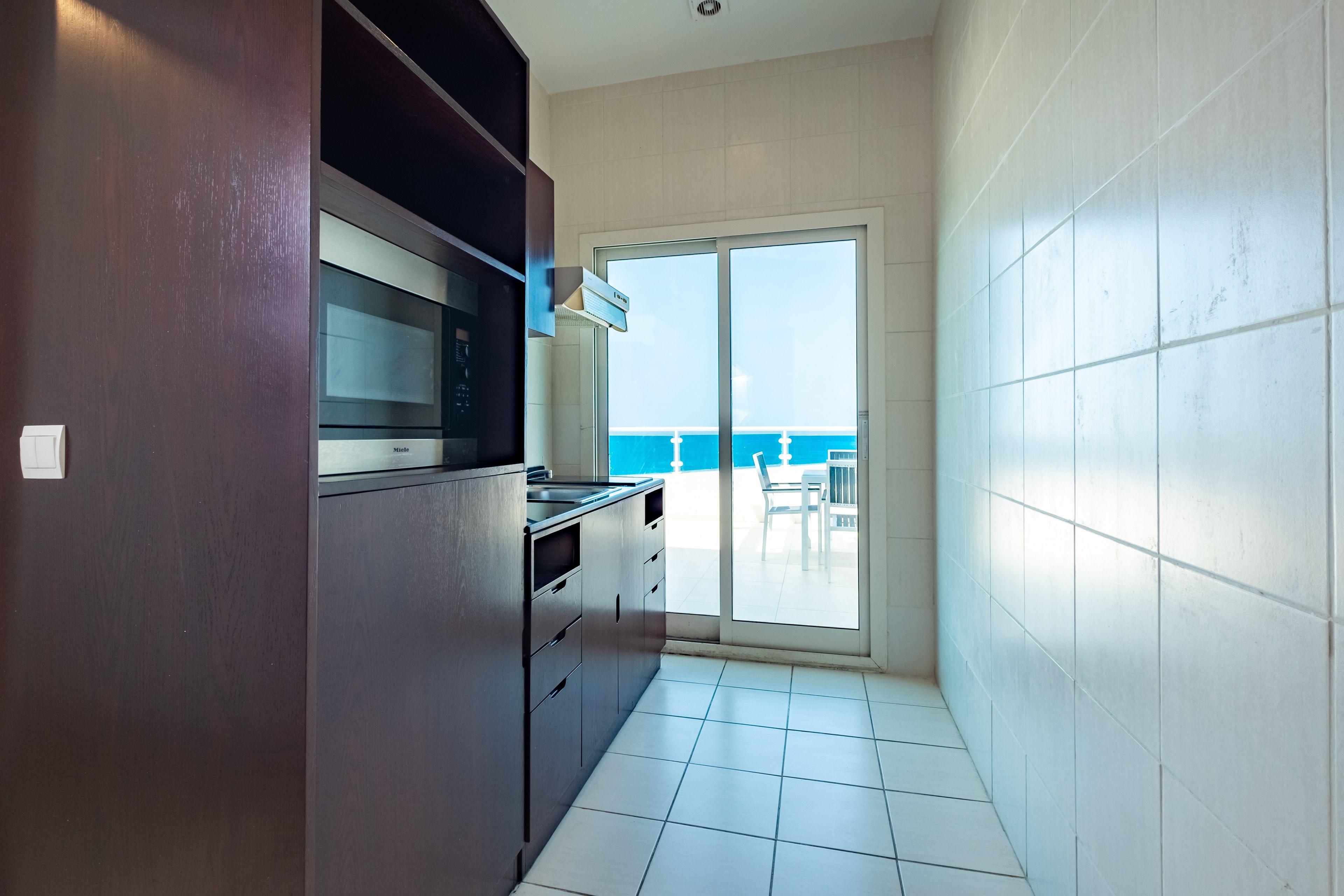 A kitchen with a view of the ocean through a sliding glass door.