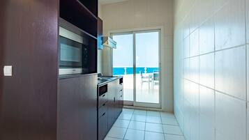 A kitchen with a view of the ocean through a sliding glass door.