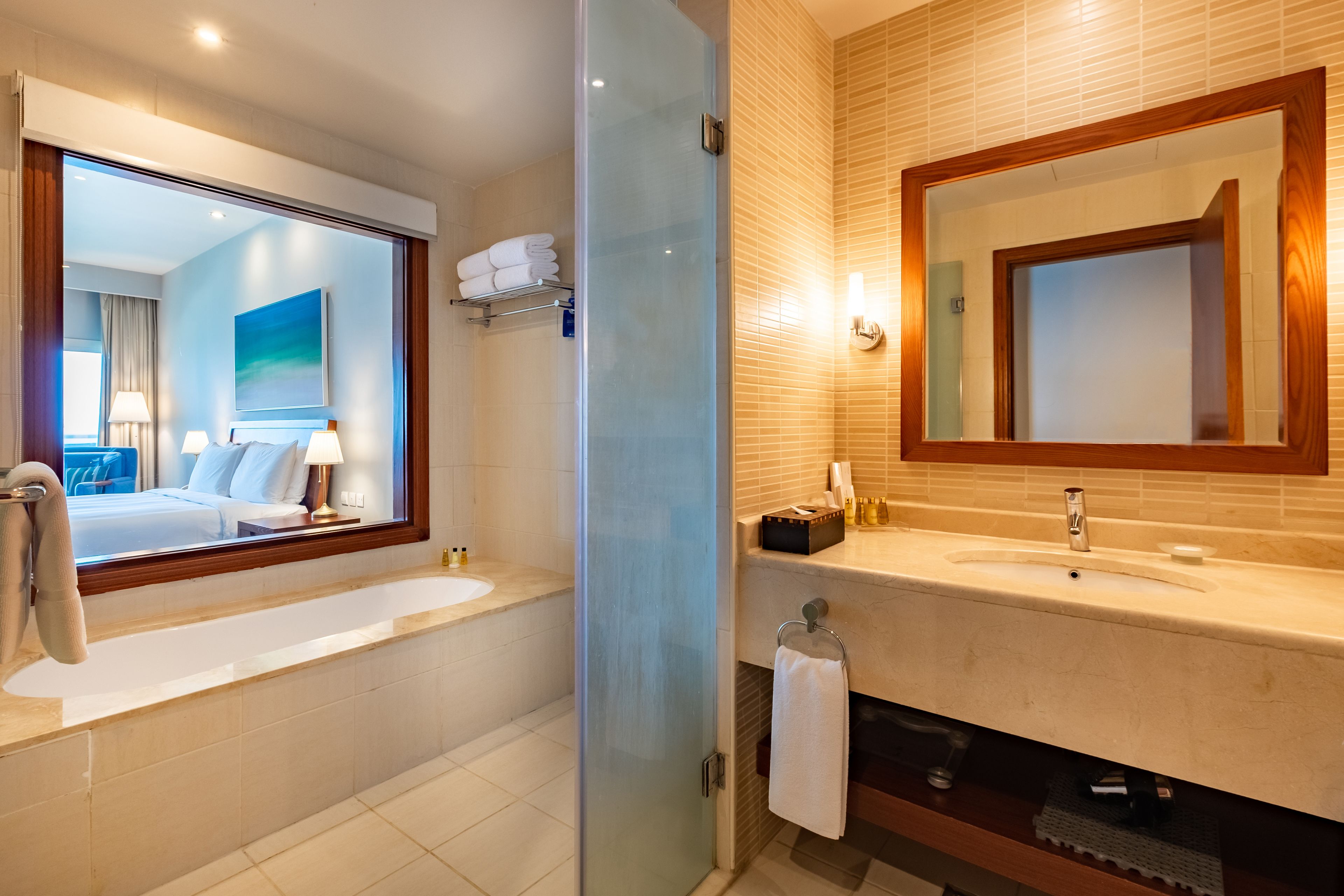 Ein modernes Badezimmer mit einer gläsernen Duschkabine, einem großen Spiegel und einer Badewanne.
