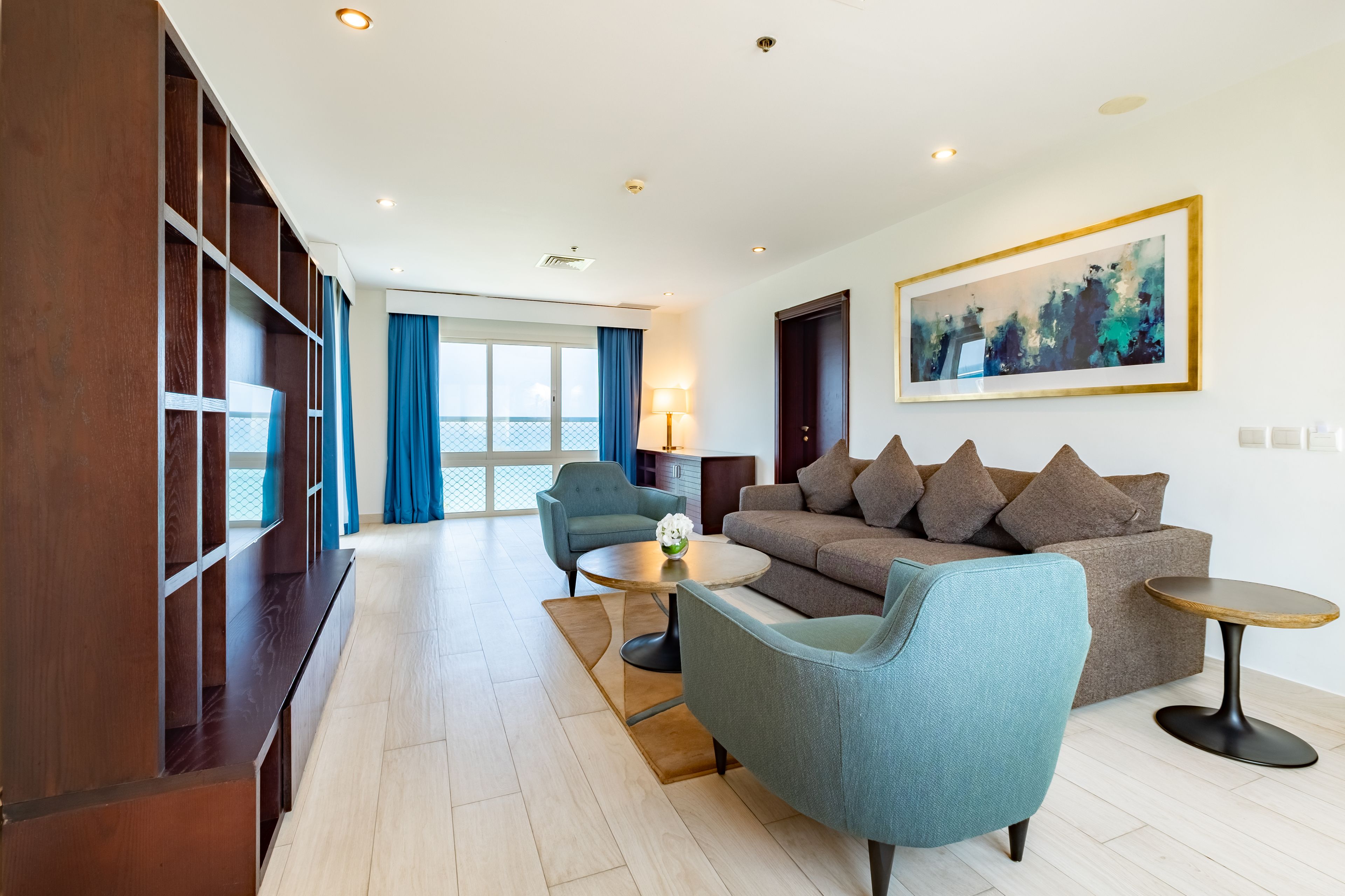 A modern living room with a sofa, two armchairs, a coffee table, and a bookshelf.