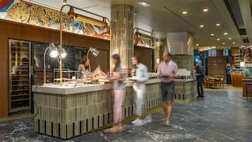 Eine moderne Hotelhalle mit einer zentralen Bar, Sitzgelegenheiten und einem Wandgemälde.
