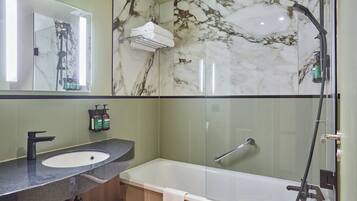Un baño moderno con salpicadero de mármol, una bañera independiente, un tocador con lavabo y un espejo.