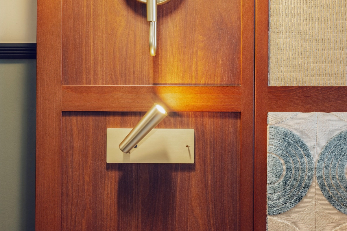 A wooden door with a brass handle and a keyhole, a light switch, and a patterned wall.