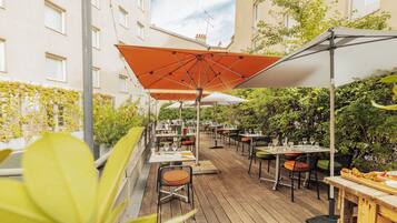 Un patio al aire libre con mesas, sillas, sombrillas y plantas.