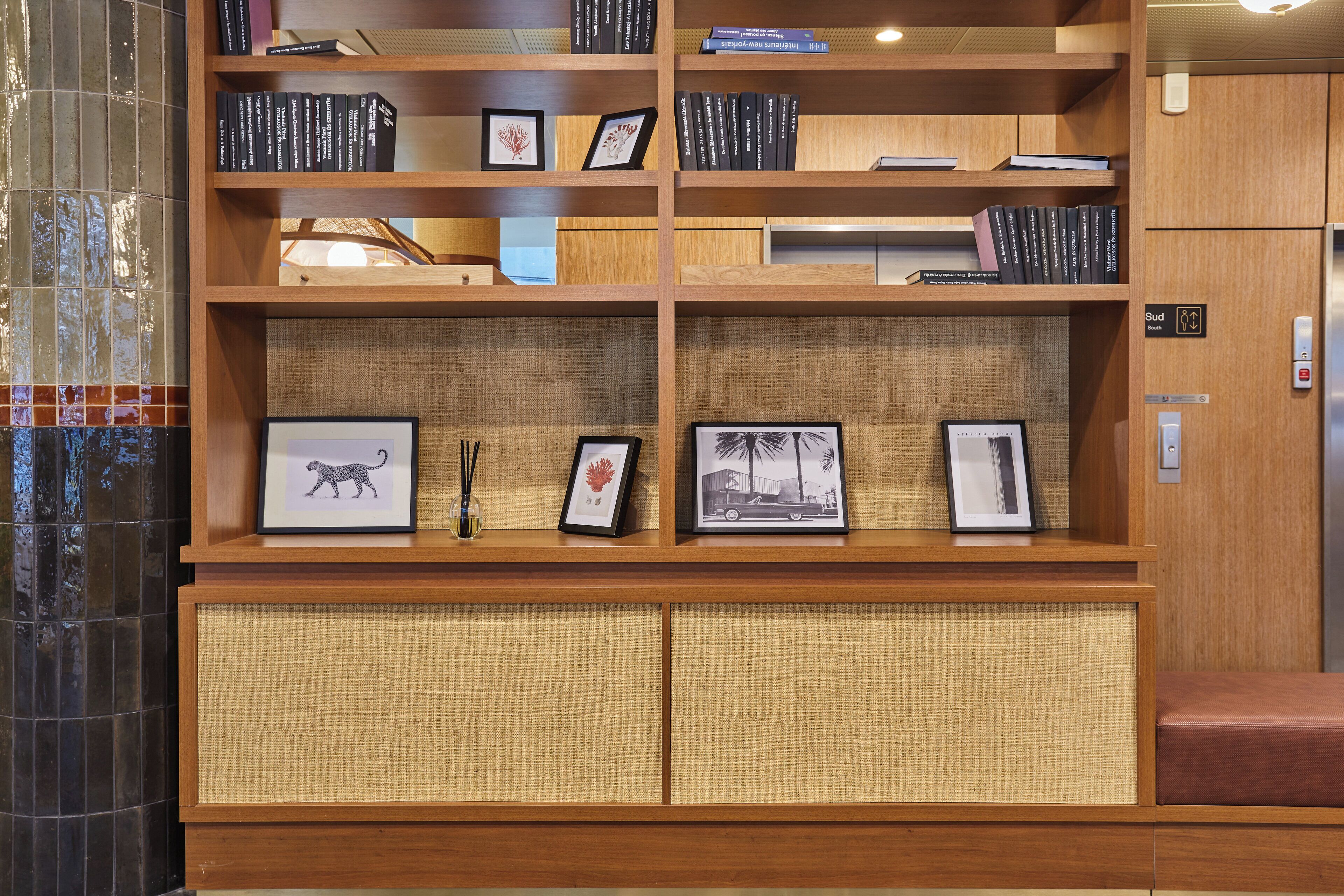 A wooden bookshelf with books and framed pictures.