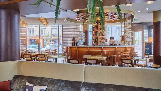 A modern restaurant with a bar area, seating arrangements, and a view of the street. - voco Paris – Porte de Clichy by IHG (Clichy)