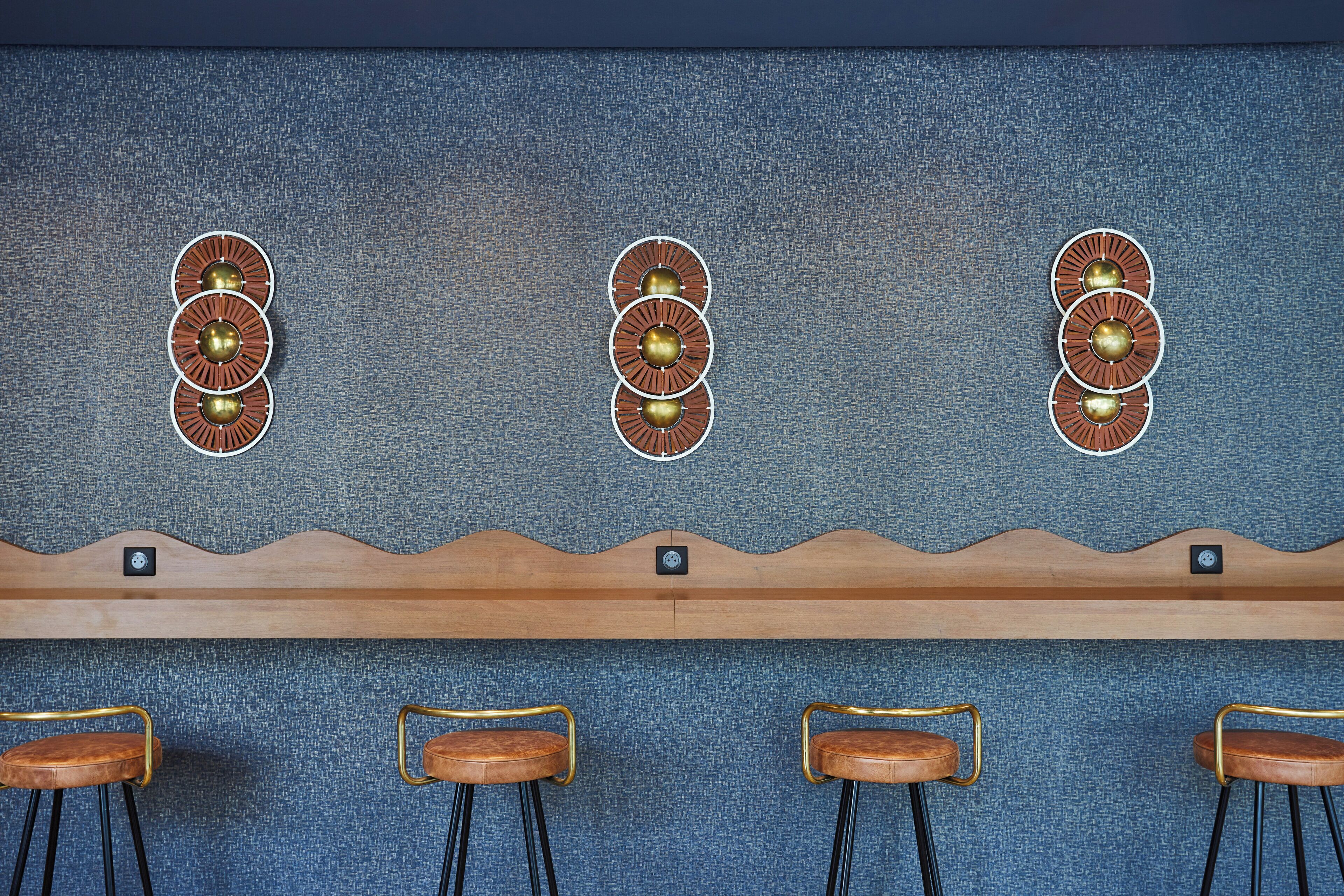 Eine Bar mit drei runden Wanddekorationen, einem Holzregal und vier Barhocker.