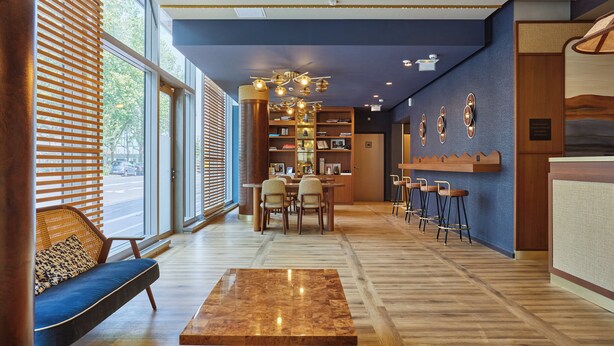A modern hotel lobby with a seating area, a bar, and a reception desk. - voco Paris – Porte de Clichy by IHG (Clichy)