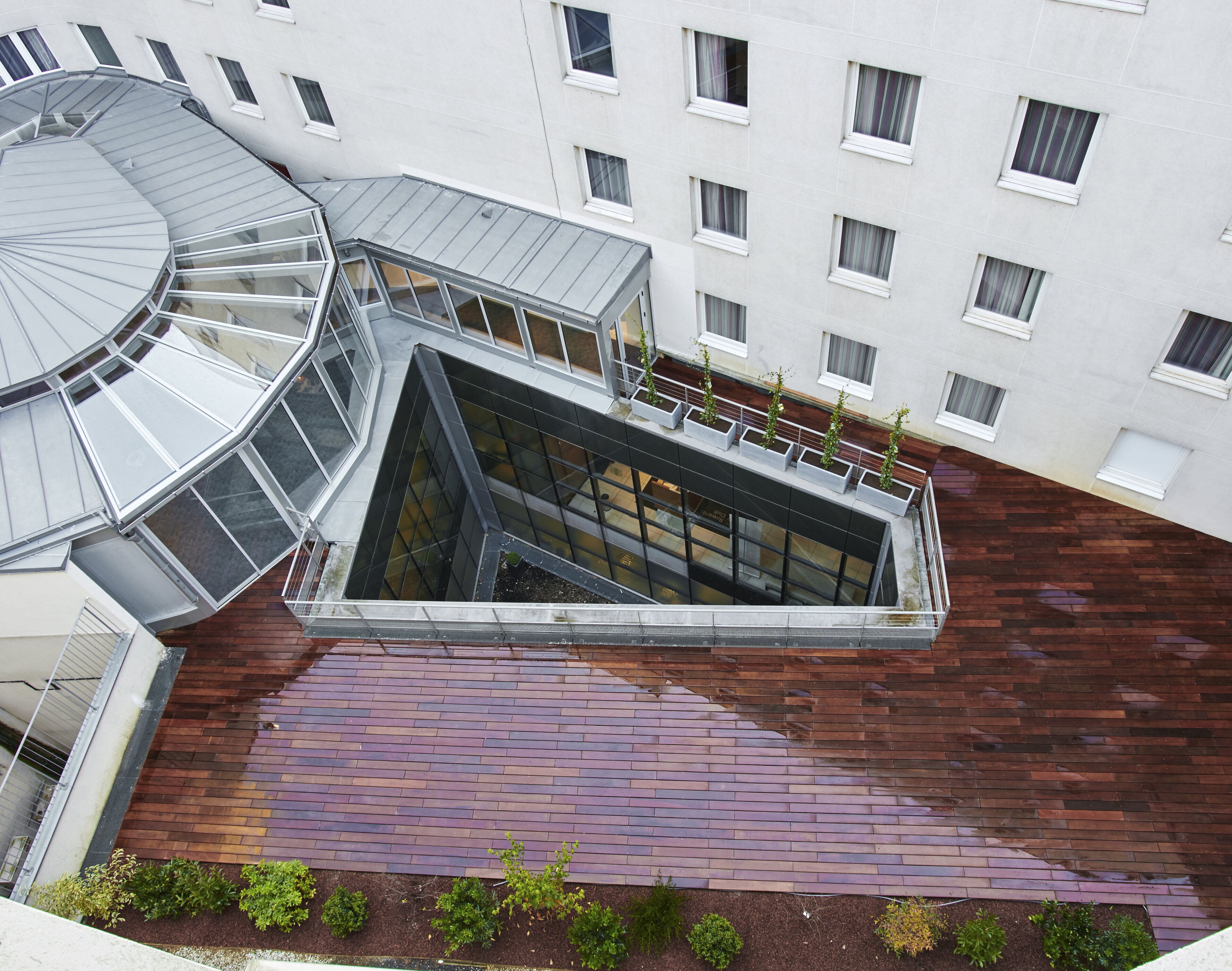 Un edificio moderno con una escalera espiral, un atrio de cristal y un techo con patrón de ladrillo.