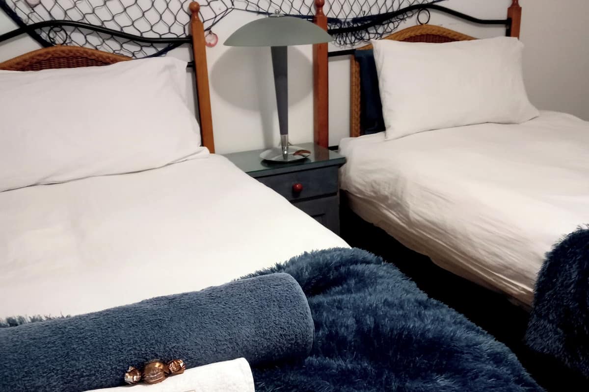 A hotel room with two beds, a nightstand with a lamp, and decorative netting on the walls.