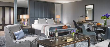 Une chambre d’hôtel moderne dotée d’un grand lit, d’un bureau et d’un coin salon avec des fauteuils et un canapé.