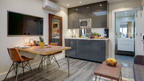 Una cocina moderna con armarios oscuros, un microondas y un comedor con mesa y sillas de madera.