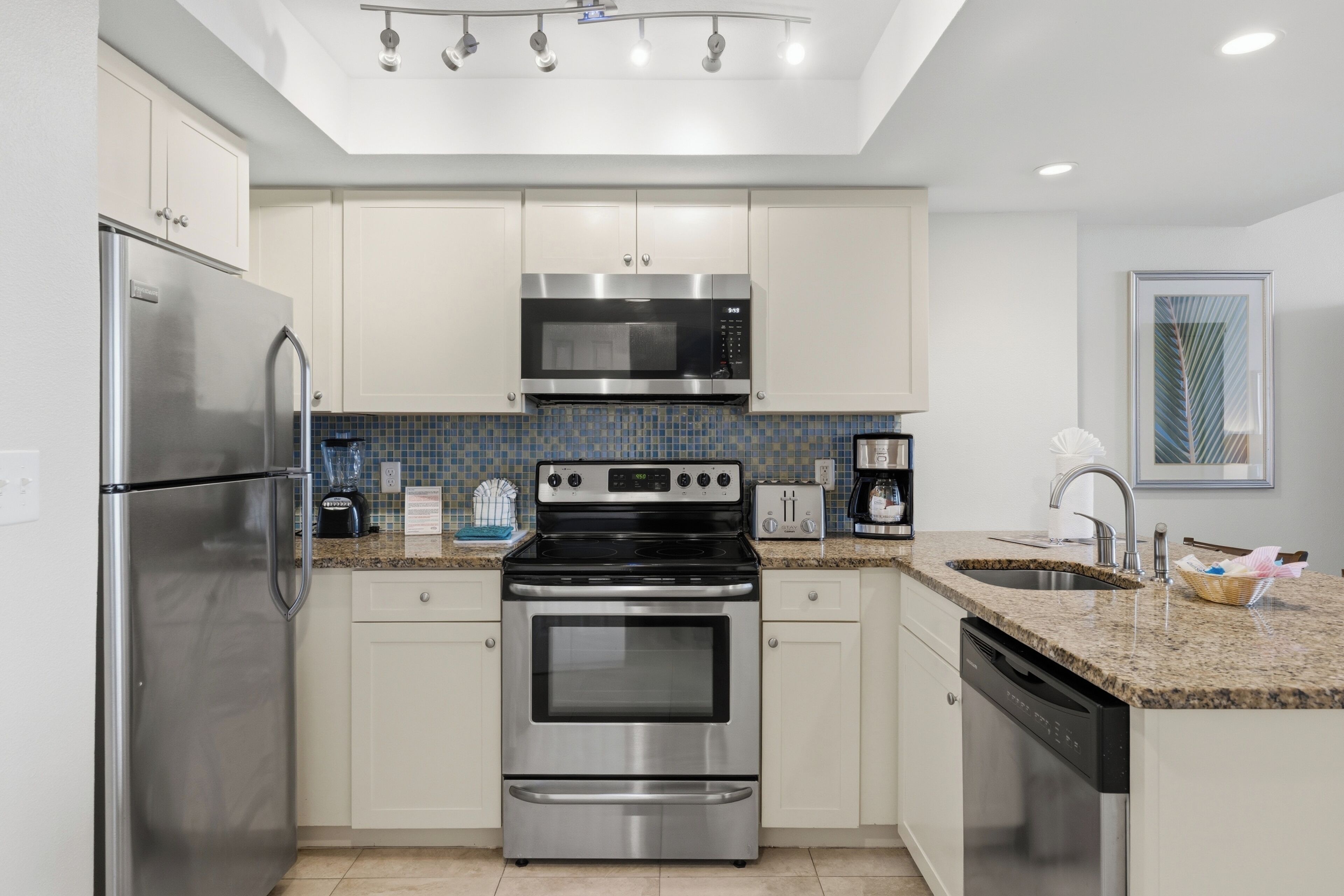 A modern kitchen with stainless steel appliances, a tiled backsplash, and a built-in oven.